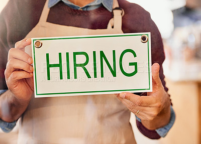 Buy stock photo Shot of an unidentifiable business owner holding up a sign that reads hiring in his shop window