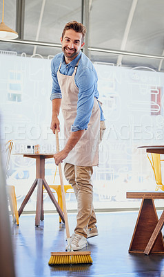 Buy stock photo Portrait of a happy business owner sweeping the floor in his coffee shop