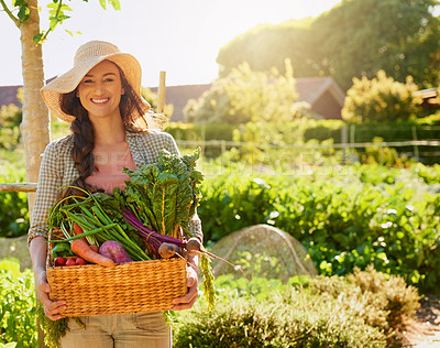 Buy stock photo Portrait of a young woman carrying a basket of freshly picked produce in a garden