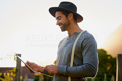 Buy stock photo Shot of a young man using a digital tablet while working in the garden