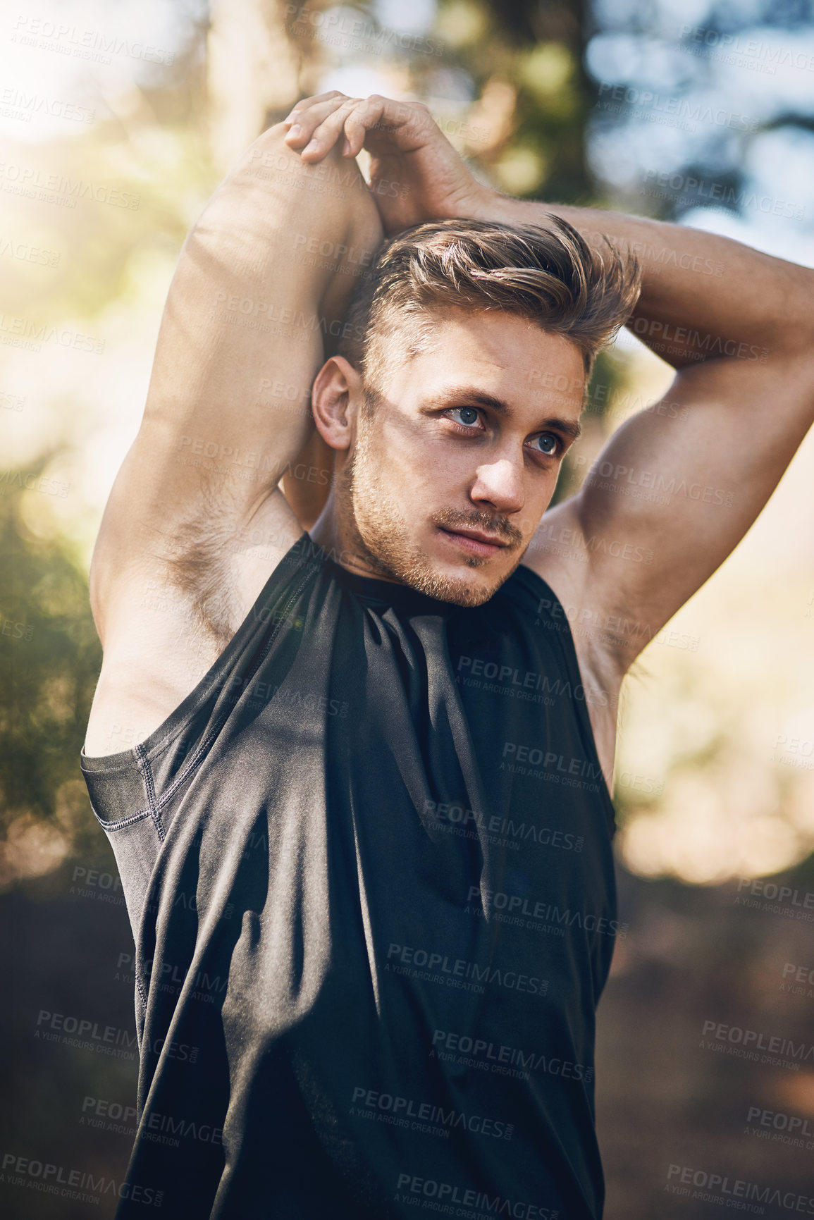 Buy stock photo Shot of a young man stretching outside in the forest