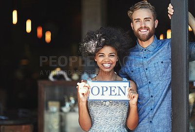 Buy stock photo Portrait of two proud coffee shop owners holding up a sign on opening day