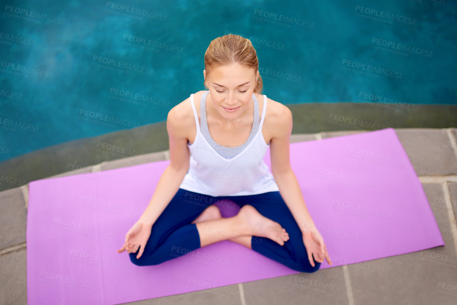 Buy stock photo Shot of a young woman doing yoga next to a swimming pool outside