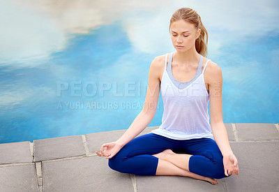 Buy stock photo Shot of a young woman doing yoga next to a swimming pool outside