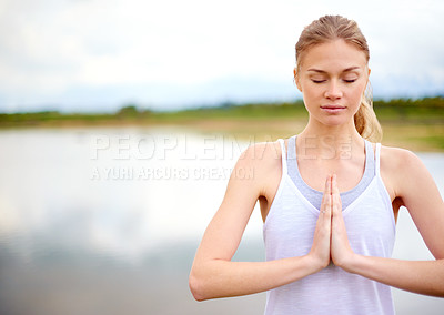 Buy stock photo Shot of a focussed young woman doing yoga next to a lake outside