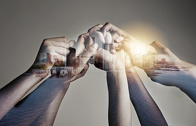Buy stock photo Shot of a city superimposed over an unidentifiable business team holding hands against a gray background