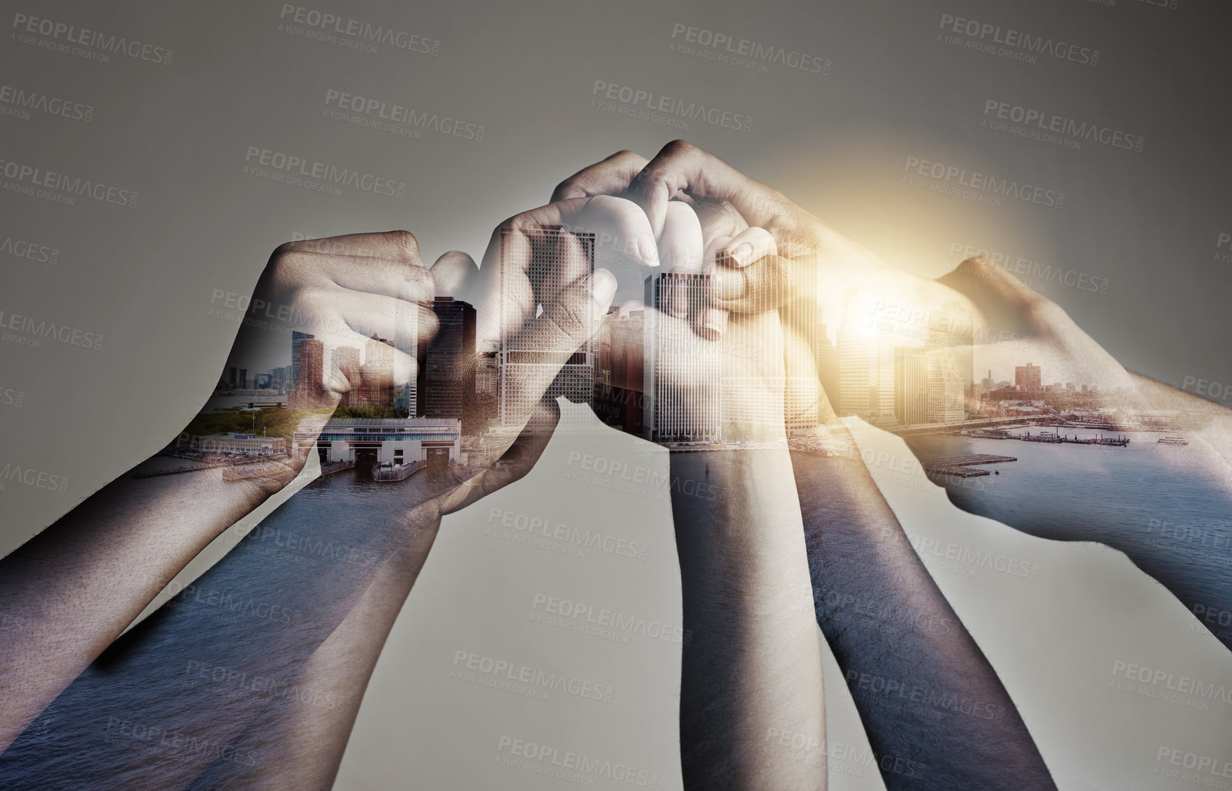 Buy stock photo Shot of a city superimposed over an unidentifiable business team holding hands against a gray background