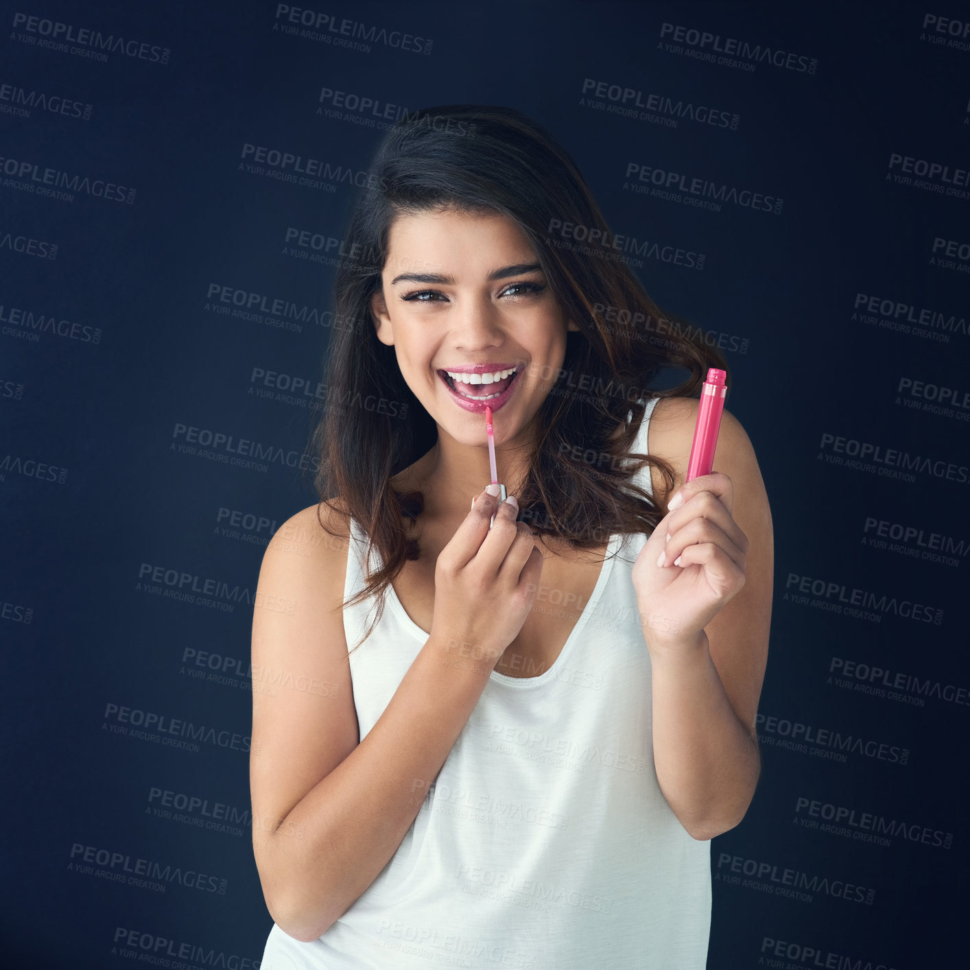 Buy stock photo Studio shot of a beautiful young woman applying lip gloss against a grey background