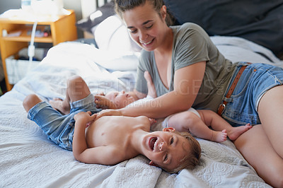 Buy stock photo Shot of a young woman bonding with her two sons at home