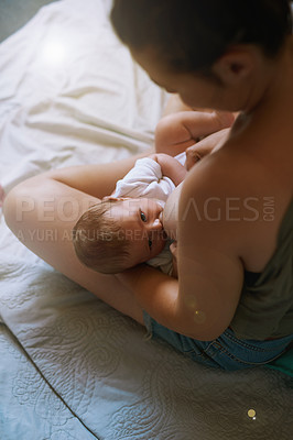 Buy stock photo Shot of a young mother breastfeeding her newborn baby at home