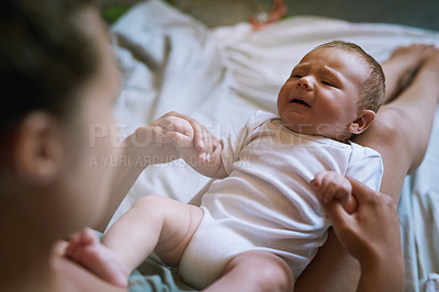 Buy stock photo Shot of a baby boy crying as he lies in his mother’s lap at home