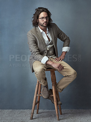 Buy stock photo Full length studio shot of a handsome and stylish young man sitting on a stool against a grey background