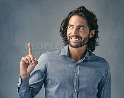 Buy stock photo Studio shot of a handsome young man pointing against a grey background