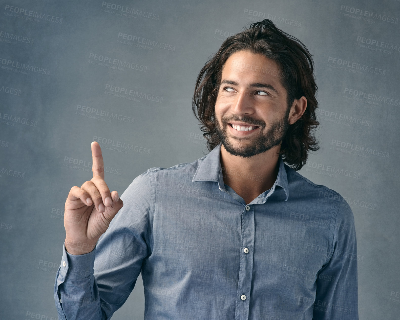 Buy stock photo Studio shot of a handsome young man pointing against a grey background