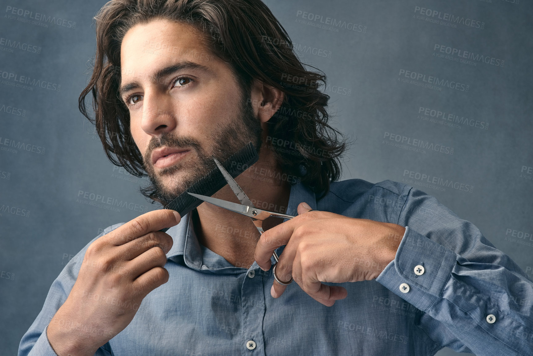 Buy stock photo Studio shot of a handsome young man cutting his beard against a grey background