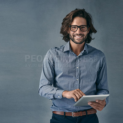 Buy stock photo Shot of a handsome young man using a digital tablet against a gray background