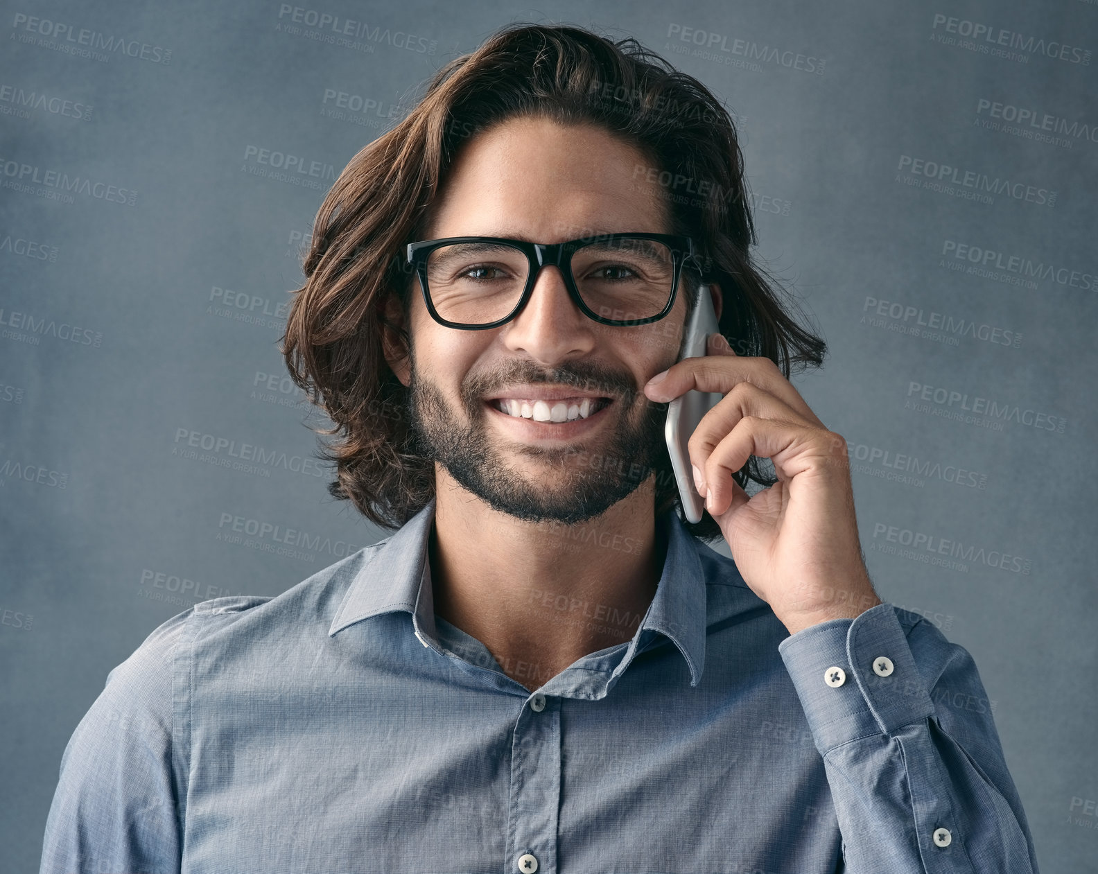 Buy stock photo Studio shot of a young man talking on his cellphone against a grey background
