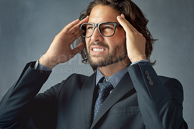 Buy stock photo Frustrated businessman, headache and stress with pain for difficult decision on a gray studio background. Young man or upset employee with migraine with mistake, pressure or strain for tough choice