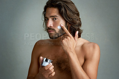 Buy stock photo Portrait, beauty or lotion with a shirtless man in studio on a gray background for his grooming routine. Skincare, facial and and the body of a handsome young person with antiaging cream for his skin