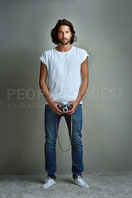 Buy stock photo Studio portrait of a handsome young man holding a vintage camera against a grey background