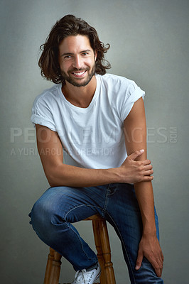 Buy stock photo Style, happy and portrait of man in studio on a stool with casual, cool and stylish outfit. Smile, handsome and confident young male model from Mexico with trendy fashion on chair by gray background.