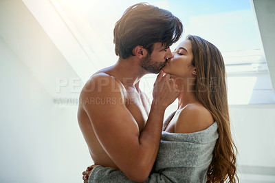 Buy stock photo Shot of an affectionate young couple kissing at home