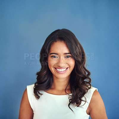 Buy stock photo Studio portrait of a confident young businesswoman posing against a blue background