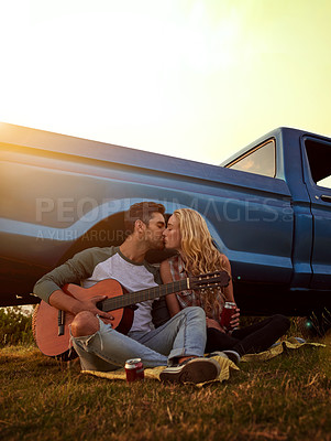 Buy stock photo Guitar, kiss and couple playing song in nature by sunset on date for romantic getaway road trip. Love, outdoor and man serenading woman with string instrument in field for vacation or holiday.