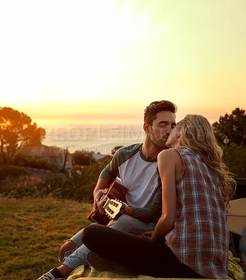 Buy stock photo Guitar, kiss and couple playing music in nature by sunset on date for romantic getaway road trip. Happy, outdoor and man serenading woman with string instrument in field for vacation or holiday.