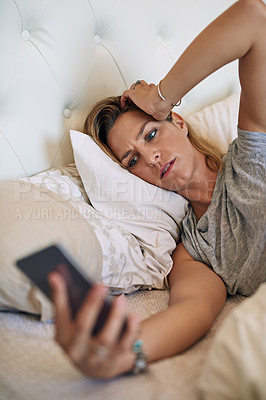 Buy stock photo Cropped shot of an attractive  woman in bed looking at her phone in worry at home