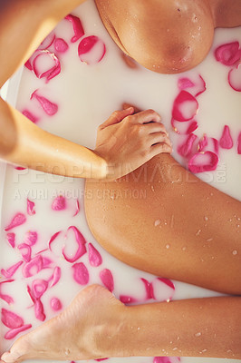Buy stock photo Cropped shot of an unidentifiable nude woman relaxing in a bathtub filled with milk and rose petals at home