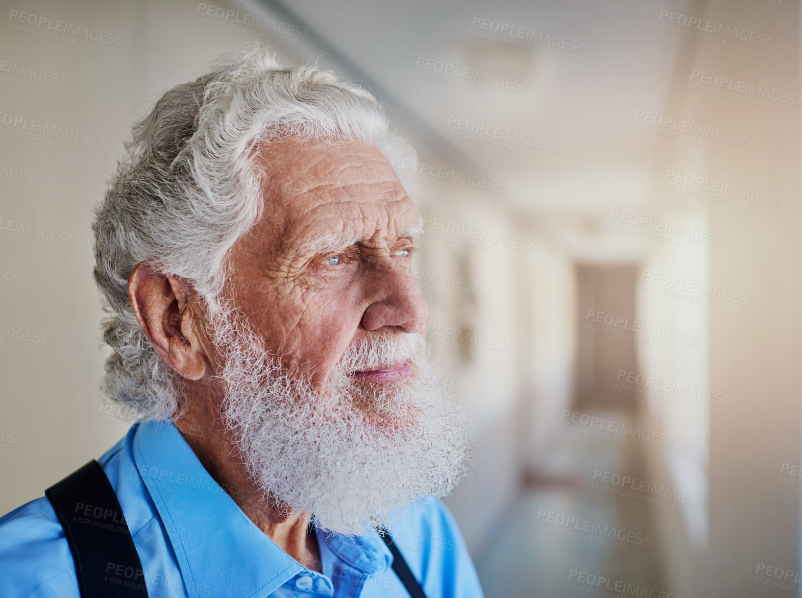 Buy stock photo Shot of a senior man looking thoughtful while standing in the hallway of his nursing home