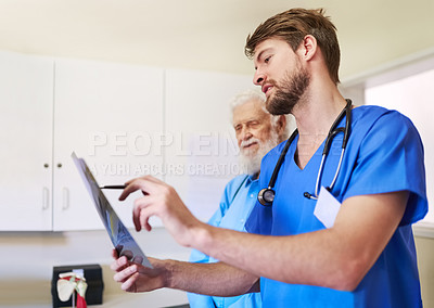 Buy stock photo Shot of a young doctor and his senior patient looking at an x-ray together