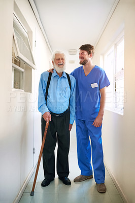 Buy stock photo Shot of a young doctor helping his senior patient walk down a hallway in hospital