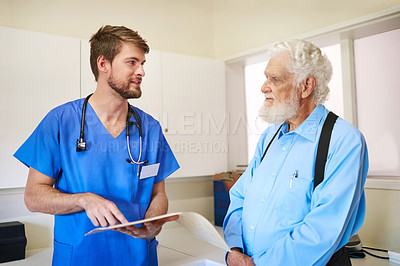 Buy stock photo Shot of a young doctor and his senior patient discussing his medical records together