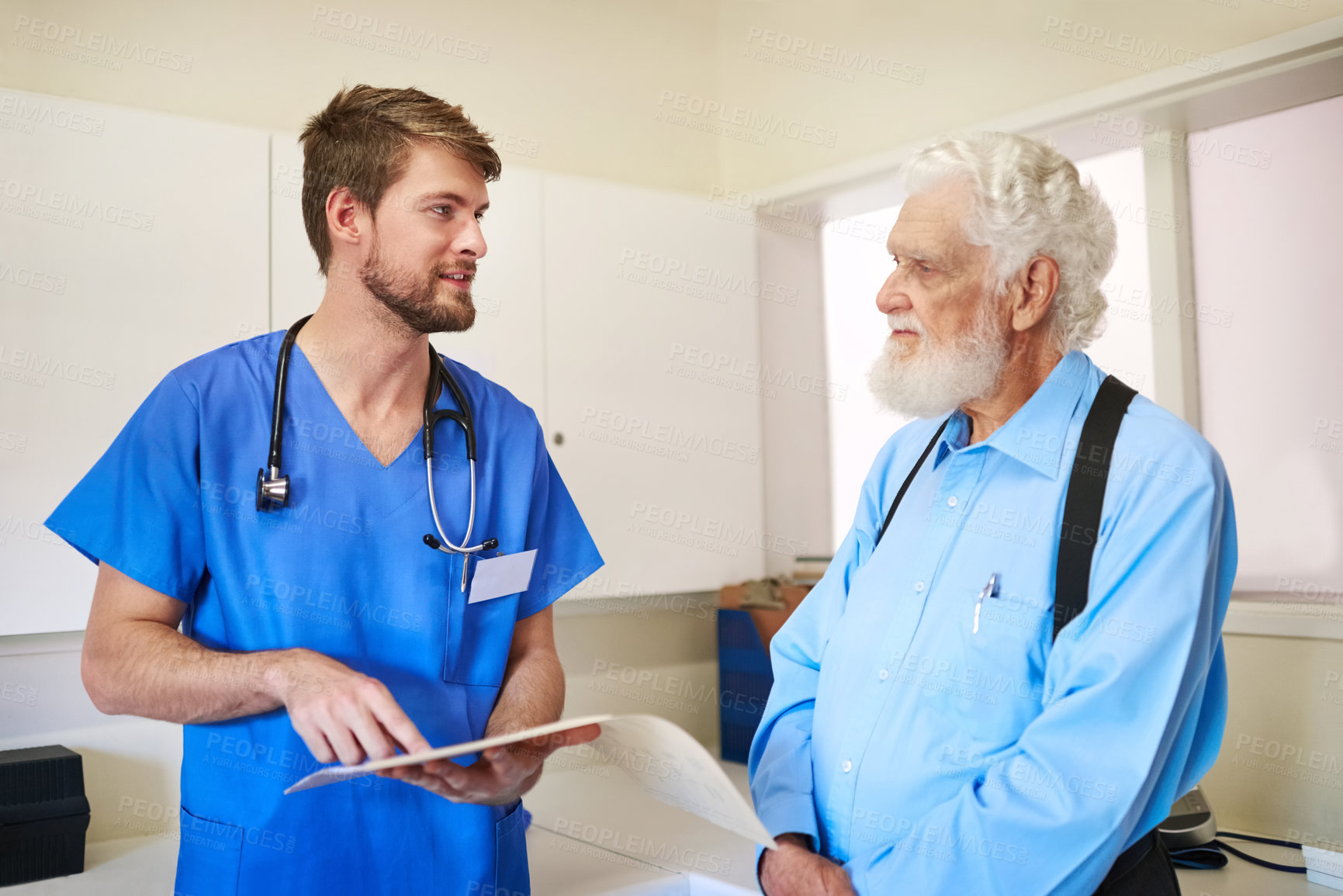 Buy stock photo Shot of a young doctor and his senior patient discussing his medical records together