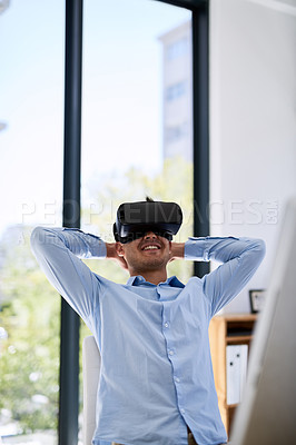 Buy stock photo Shot of a happy young businessman wearing a virtual reality headset while working at his desk in the office