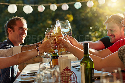 Buy stock photo Shot of a group of happy young friends toasting with wine at a backyard dinner party