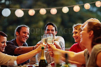 Buy stock photo Shot of a group of happy young friends toasting with champagne at a backyard dinner party
