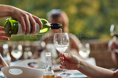 Buy stock photo Shot of an unidentifiable young man pouring wine in his friend's glass at a backyard dinner party