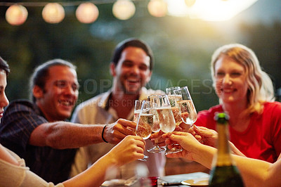 Buy stock photo Shot of a group of happy young friends toasting with champagne at a backyard dinner party