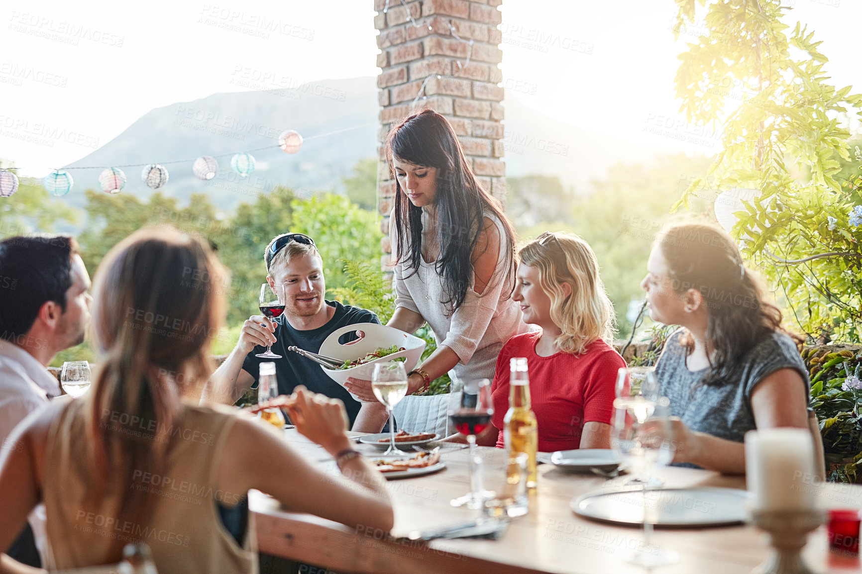 Buy stock photo Shot of a group of happy young friends sharing a meal at a backyard dinner party