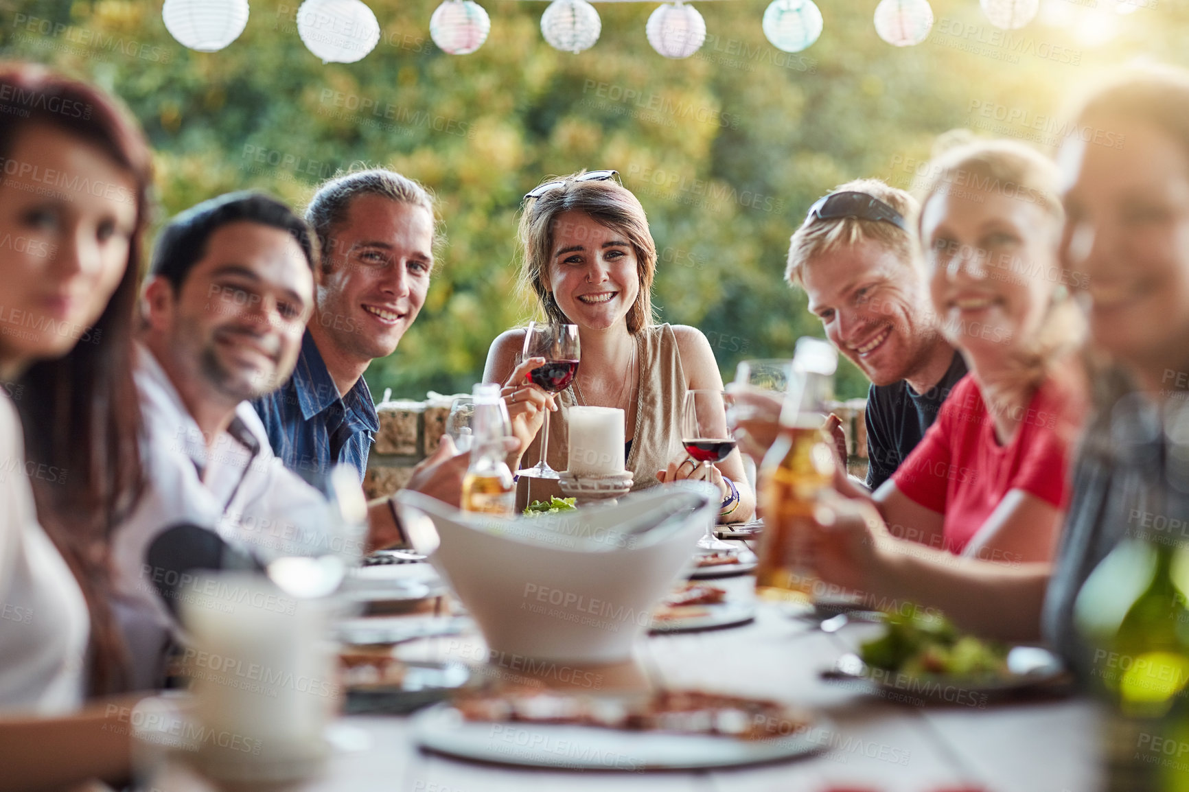 Buy stock photo Portrait of a group of happy young friends sharing a meal at a backyard dinner party