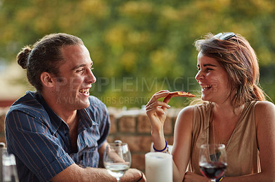 Buy stock photo Shot of two happy young friends sharing a pizza outside
