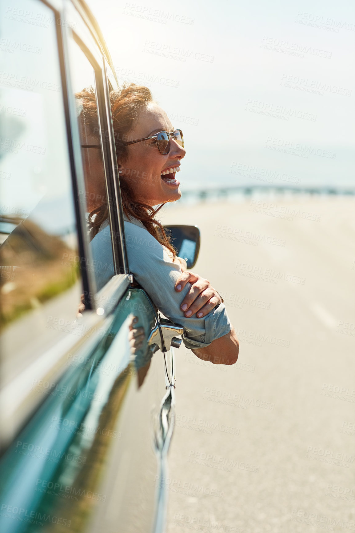 Buy stock photo Cropped shot of an attractive woman hanging out of a car window while enjoying a roadtrip