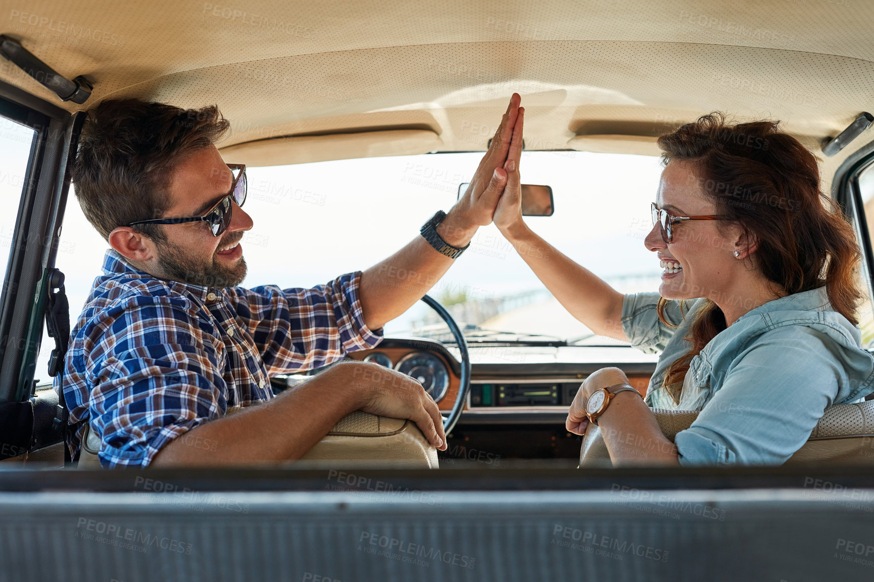 Buy stock photo Rearview shot of an affectionate couple giving each other a high five while enjoying a roadtrip