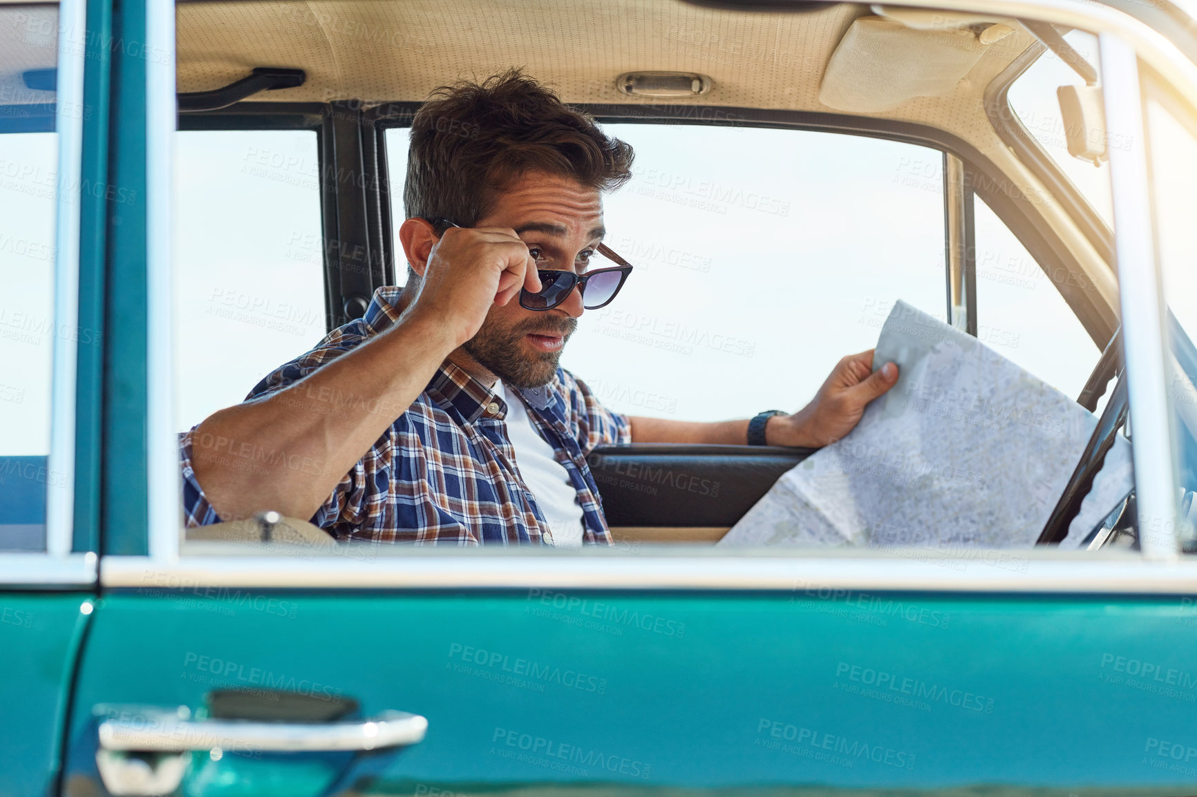 Buy stock photo Cropped shot of a handsome man checking a map while enjoying a roadtrip