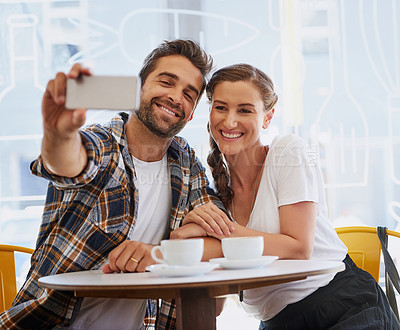 Buy stock photo Shot of a happy young couple posing for a selfie together in a coffee shop