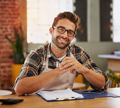 Buy stock photo Portrait of a happy young business owner doing admin at a table in his coffee shop