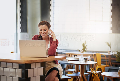 Buy stock photo Shot of a happy young business owner doing admin at a table in her coffee shop